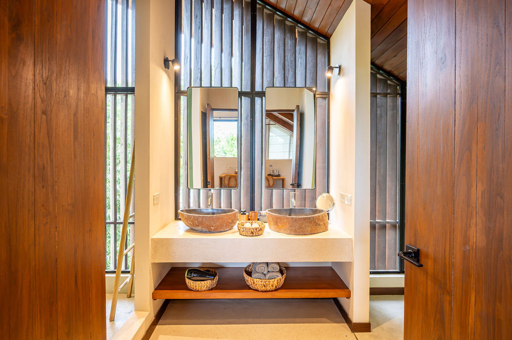 Teak double vanity with stone basins and black-framed mirrors